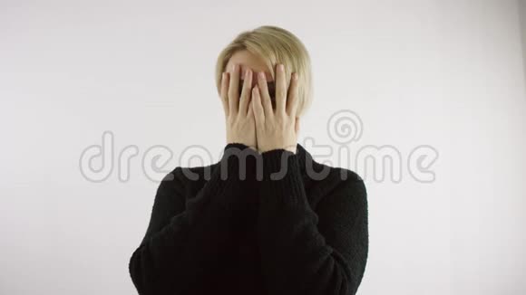 成年白种人白种人金发女子正在明亮的室内用双手遮住她的脸视频的预览图