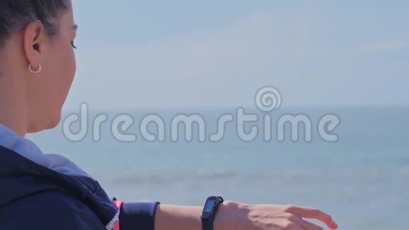 在海滩锻炼时看她的智能手表的女人视频的预览图