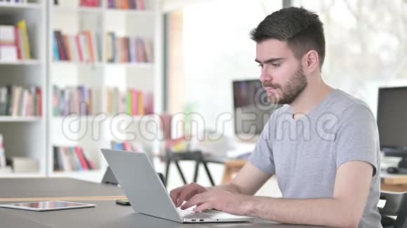 在办公室咳嗽的年轻人用笔记本电脑视频的预览图