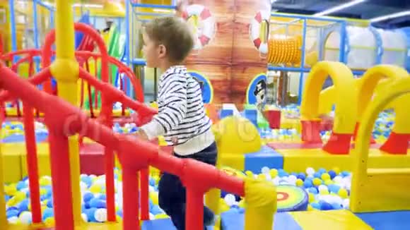4k镜头4岁小男孩在购物中心五颜六色的大儿童游乐场玩耍和散步视频的预览图