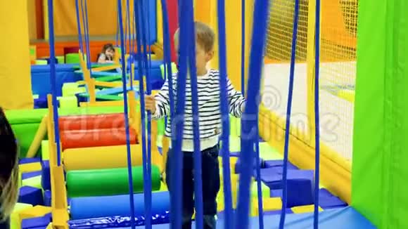 在游乐园儿童游乐场里小男孩在摇晃的绳桥上行走视频的预览图