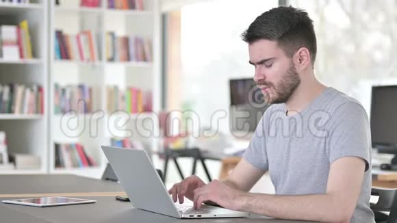 有脖子疼的年轻人在办公室用笔记本电脑视频的预览图