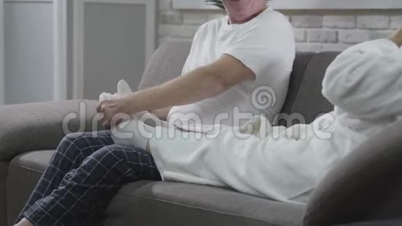 无法辨认的积极成熟男人坐在沙发上按摩妻子脚丈夫照顾他的高级妻子视频的预览图