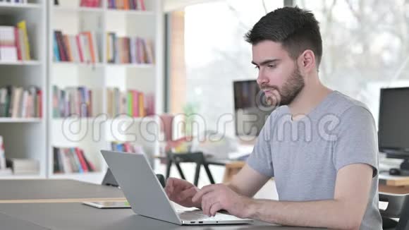 有笔记本电脑的年轻人在办公室里对着镜头微笑视频的预览图