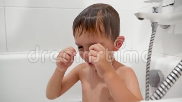 小男孩洗澡时揉眼睛和感到眼睛疼痛的特写慢动作视频视频的预览图