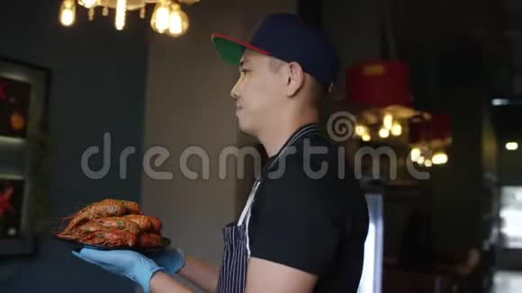 一位戴着帽子的年轻厨师正在一家餐馆里向摄像机展示一盘美味的龙虾跟踪弧线拍摄360视频的预览图
