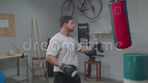 疲惫的男人在健身房拿着一个拳击袋视频的预览图