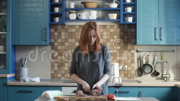 女孩切烟熏香肠用刀子在现代厨房的木板上做三明治视频的预览图
