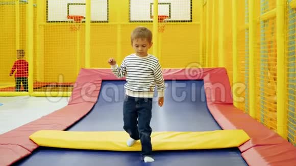 在购物中心的游乐园里欢快的小男孩在蹦床上玩耍和跳跃视频的预览图