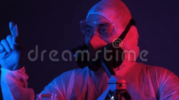 戴着实验室面罩和手套的男工程师在霓虹灯中持有计算机处理器视频的预览图