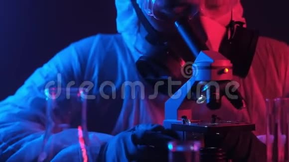 戴面具的科学家在显微镜下观察霓虹蓝红色灯光视频的预览图