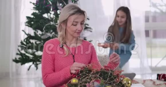 可爱的白人女孩带着圣诞礼物来到母亲身边幸福的金发女人对女儿惊讶视频的预览图