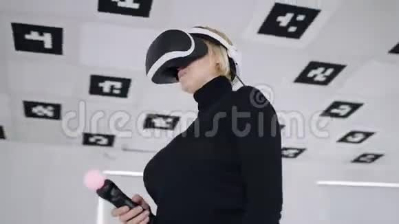 成年女性在虚拟现实耳机中跳舞在充满白色霓虹灯的空玩室里使用控制器视频的预览图