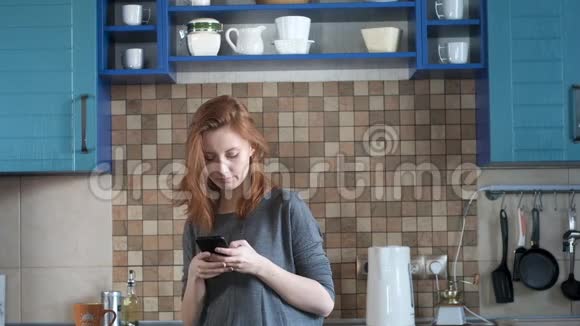 一个红发女孩喝着咖啡在智能手机上写了一条信息视频的预览图