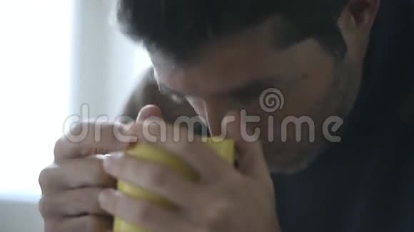 24fps视频镜头手拿相机特写年轻人在家看起来悲伤喝咖啡视频的预览图