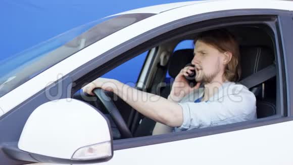 愤怒的男子正在与某人在电话中争论而驾驶一辆白色汽车与蓝色屏幕背景布鲁内特先生视频的预览图
