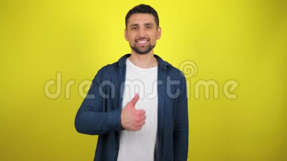 一个穿着蓝色衬衫和白色T恤的年轻人看着相机微笑着用双手表现出来视频的预览图