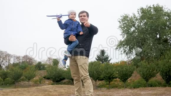 4k视频快乐微笑的小男孩在公园草地上玩耍时在高空发射玩具飞机视频的预览图