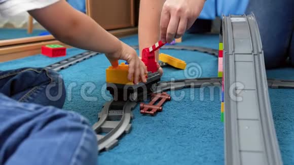 特写4k小妈妈的视频小男孩在地上玩玩具铁路和砖块视频的预览图