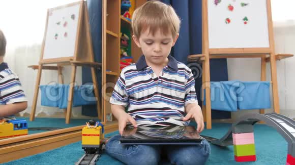 4k视频小男孩坐在地毯上的hid游戏室和玩电子游戏的数字平板电脑视频的预览图