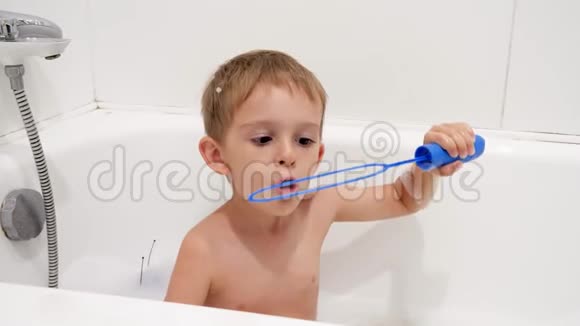4k慢动作视频快乐的小男孩坐在浴缸里用泡沫和肥皂泡视频的预览图
