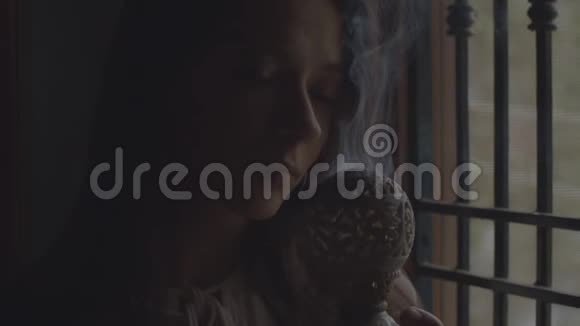 冥想的女孩在黑暗的寺庙里靠窗慢动作烧着香炉冥想闻到印度香味的年轻女子视频的预览图