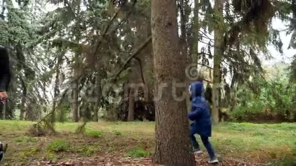 4k视频快乐的笑妈妈和小儿子在秋天公园的树间奔跑互相追逐视频的预览图