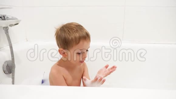 4k镜头快乐地笑着蹒跚学步的男孩在洗澡时洗澡手上放着肥皂泡视频的预览图