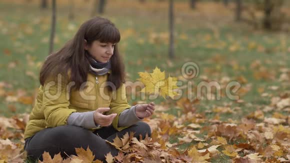 秋天女人手里拿着黄色的枫叶想着慢动作视频的预览图