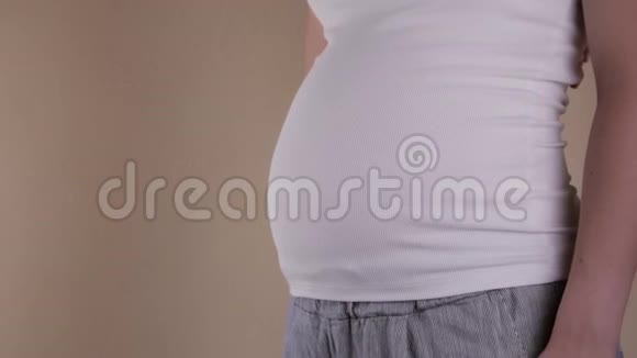 一个孕妇穿着白色T恤的腹部的特写镜头显示出类似的标志文本复制空间视频的预览图