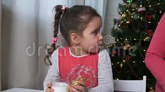 可爱的宝宝带着姜饼饼干和一杯牛奶传统的圣诞大餐食物视频的预览图