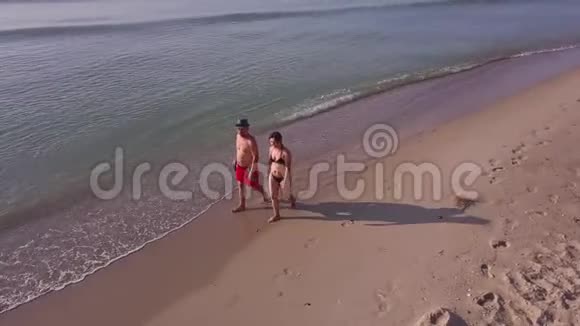 男人和女人在日落时沿着海滩散步视频的预览图