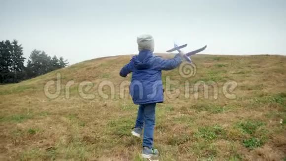 4k视频快乐小男孩拿着玩具飞机在公园的山顶上奔跑视频的预览图