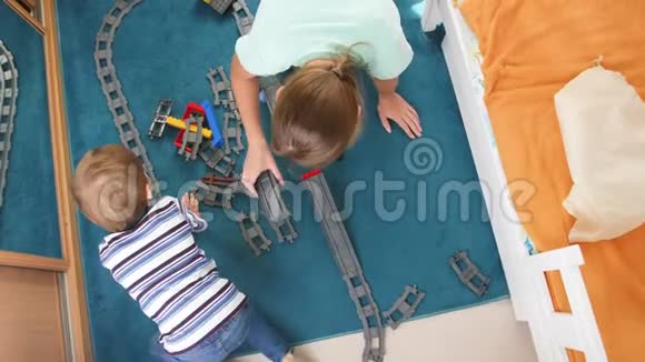 从高处看家庭坐在地板上在卧室里建造和组装玩具铁路视频的预览图
