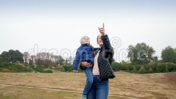 4k视频年轻母亲抱着小儿子在公园里仰望蓝天视频的预览图