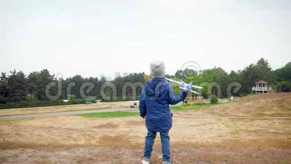 快乐微笑的小男孩站在山顶玩玩具飞机的慢动作视频视频的预览图