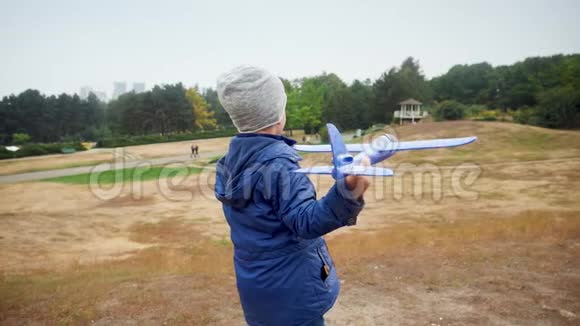 小男孩在草地上投掷玩具飞机的慢动作视频视频的预览图