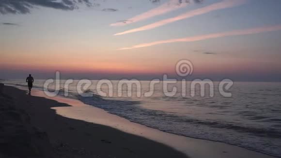 剪影日出时一个人平静地走在荒芜的海滩上视频的预览图
