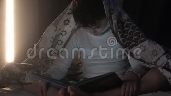 男孩盖着毯子晚上在床上卧室看书视频的预览图