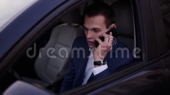 一个男人坐在驾驶座上手里拿着一部智能手机一个商人坐着说话视频的预览图