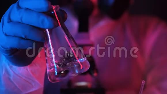 科学家或化学家在实验室里用霓虹灯摇动烧杯中的液体视频的预览图