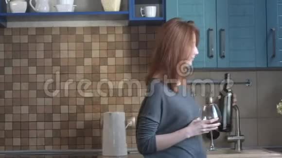 漂亮的小女孩在厨房里用玻璃杯喝红酒视频的预览图