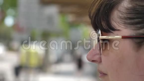 一个戴着太阳镜的快乐女人的肖像看着街上路过的人视频的预览图