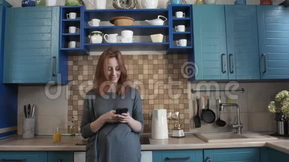 女人早上喝新鲜橙汁在智能手机上写信息视频的预览图