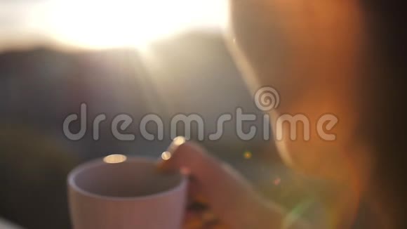 女人在阳台上喝咖啡欣赏日落慢动作视频的预览图