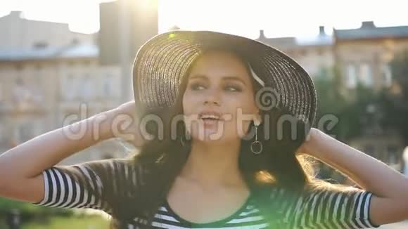 夕阳西下一位留着长发戴着黑帽子的迷人女士在街上散步视频的预览图