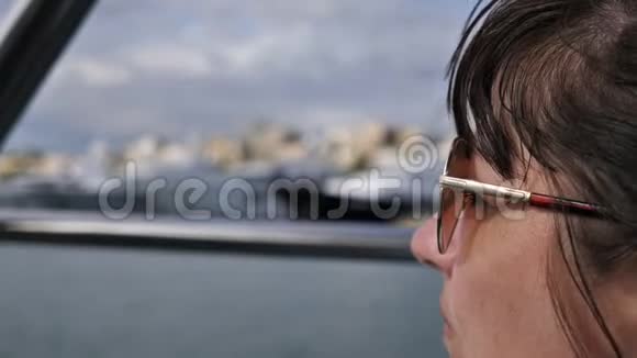 戴墨镜的旅行妇女在船上漂浮环顾四周视频的预览图
