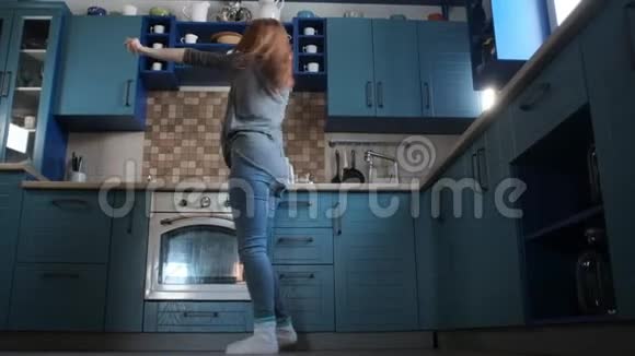 穿着休闲服的漂亮女人正在舒适的厨房里精力充沛地跳舞视频的预览图