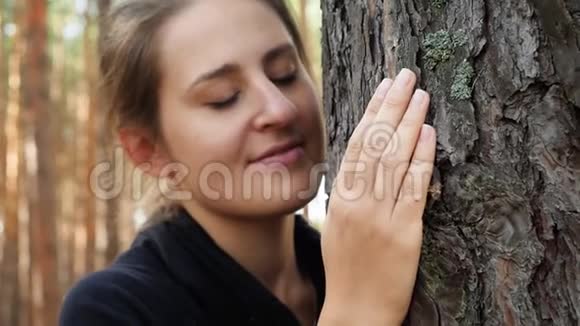 年轻女子用手轻轻触摸森林中舒缓的大树的4k特写视频热爱人民的观念视频的预览图