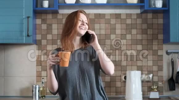 戴着红色头发的白人女孩在智能手机上笑女孩喝咖啡视频的预览图